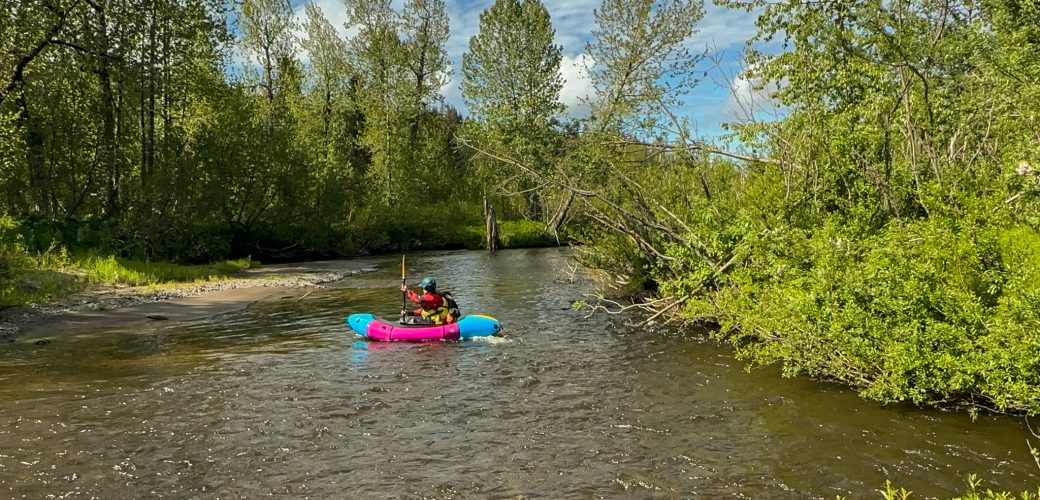 Bright canoe with individual paddling down one of the rivers surrounded by lush forest